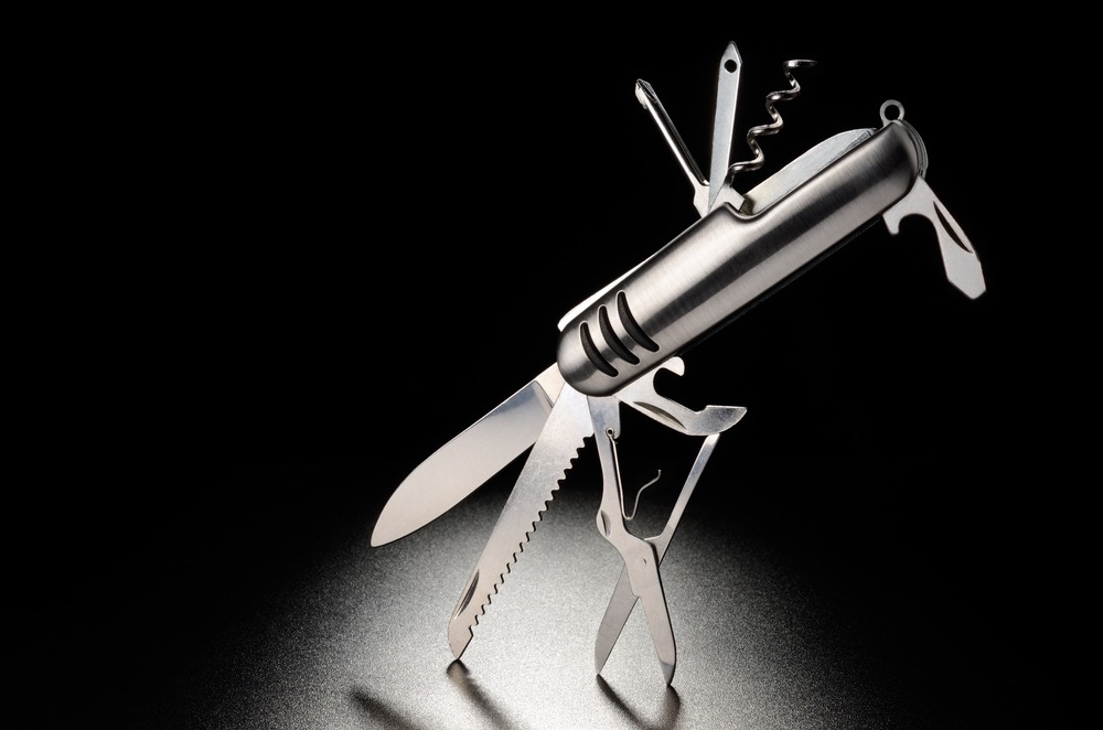 A Swiss Army knife showcasing its various tools, illuminated against a dark background
