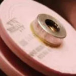 Pink circular grinding wheel or polishing disc with metal center attachment for power tools.
