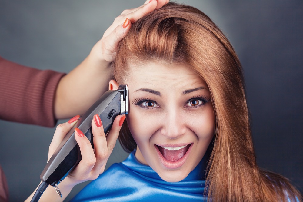 woman is shaving her hair using trimmer