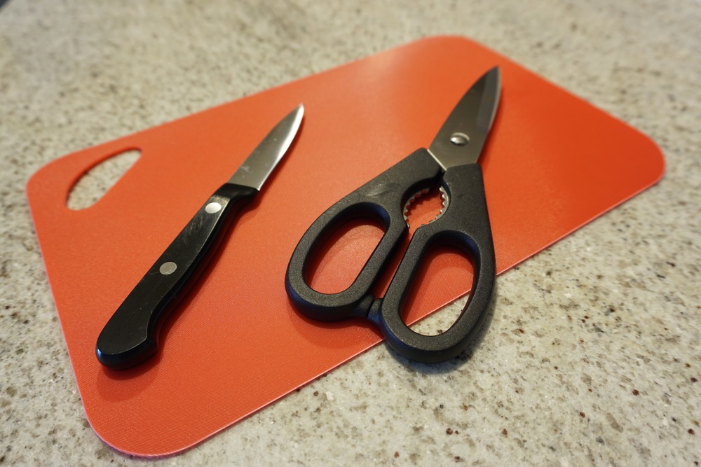 knife and scissor on orange color chopping board