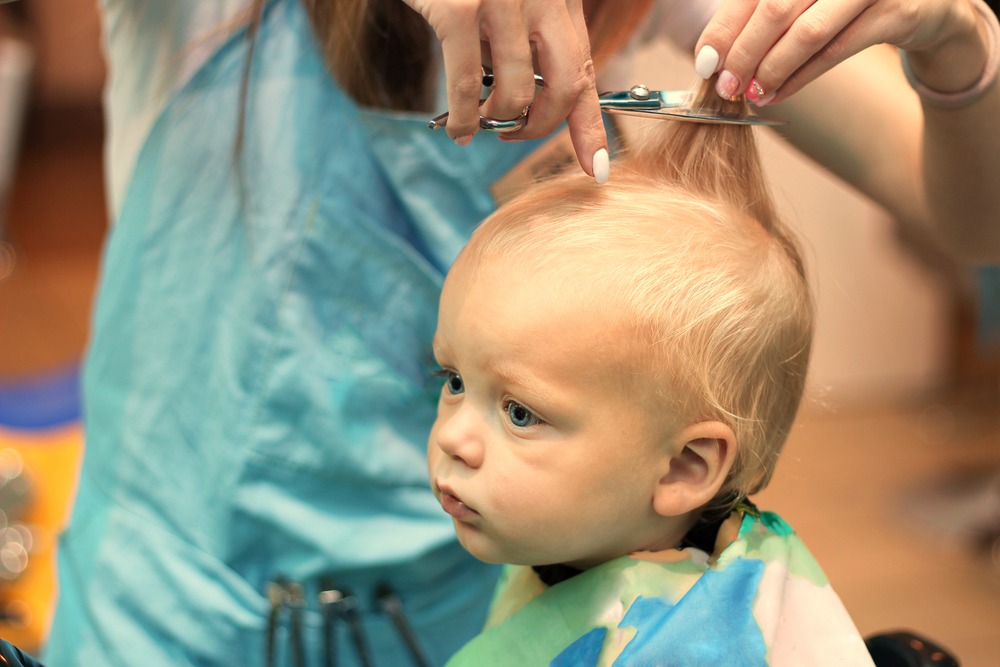 a woman cutting kids hair using scissor